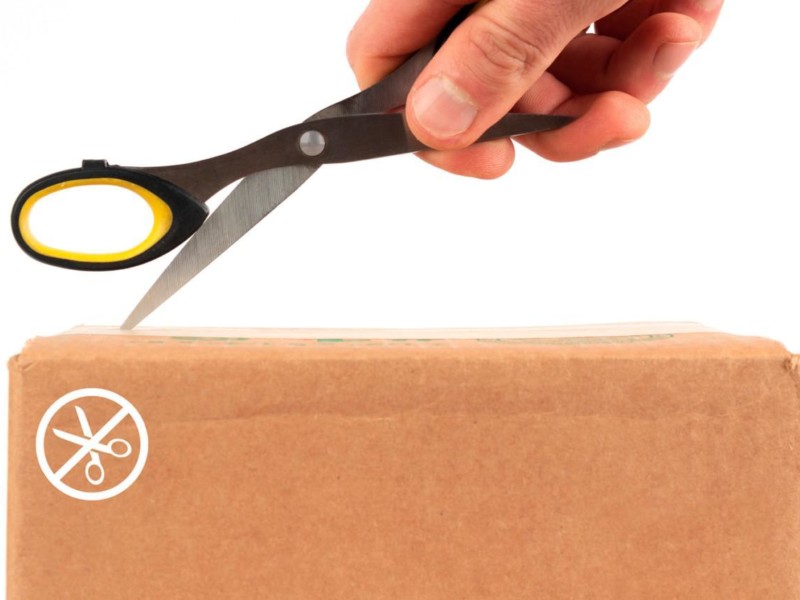 Cutting into a box with a pair of open scissors, with a "no scissors" warning on the box.